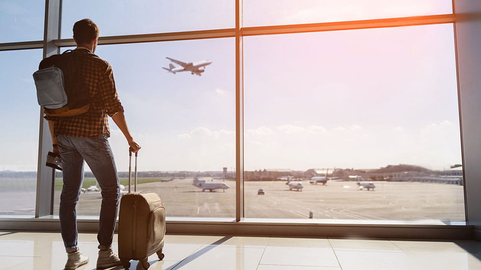 man looking out airport with airplane landing